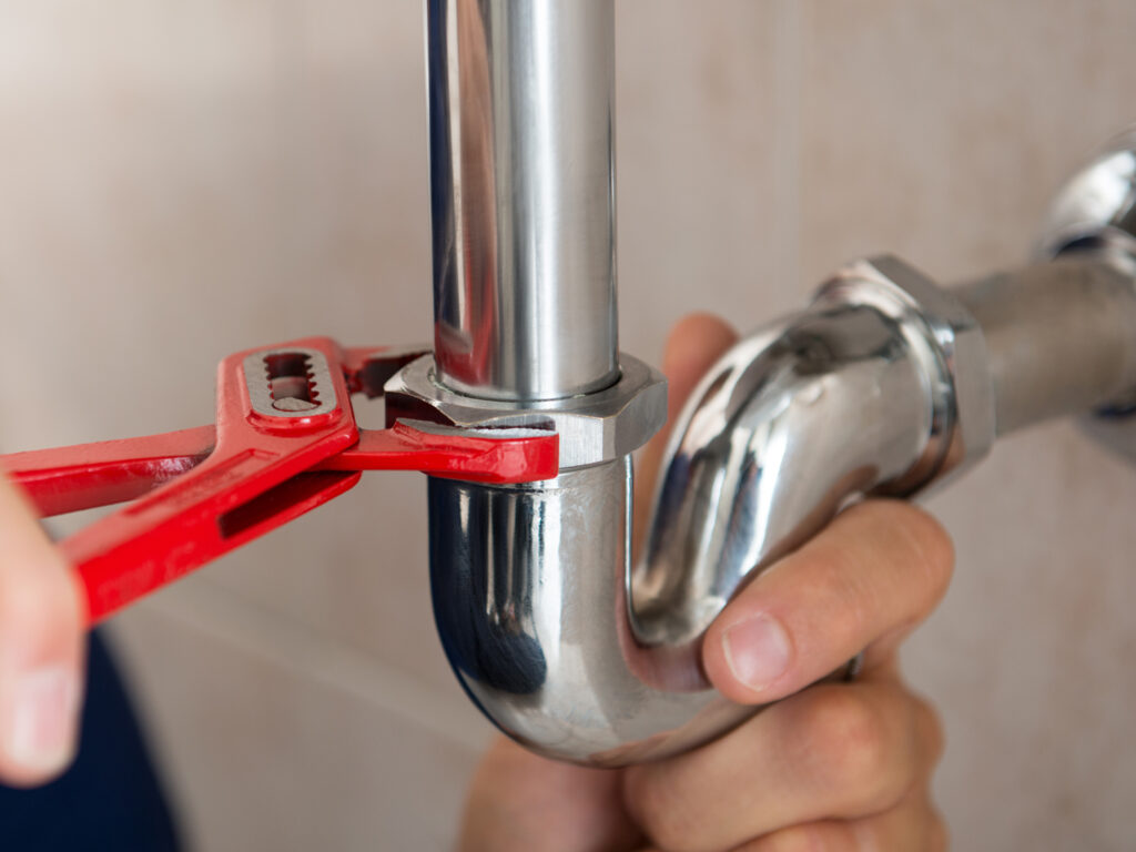 Closeup Of Plumber Fixing Pipe With Wrench