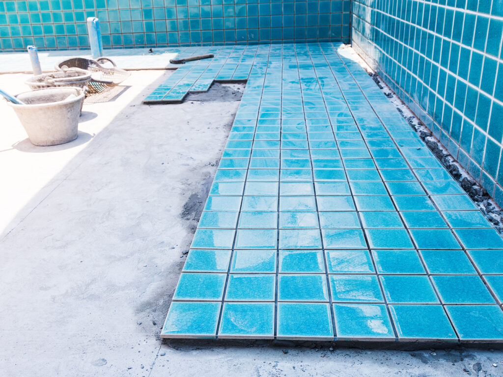 Industry building construction architecture worker professional man builder are installation blue swimming pool ceramic tiles on cement concrete floors and wall